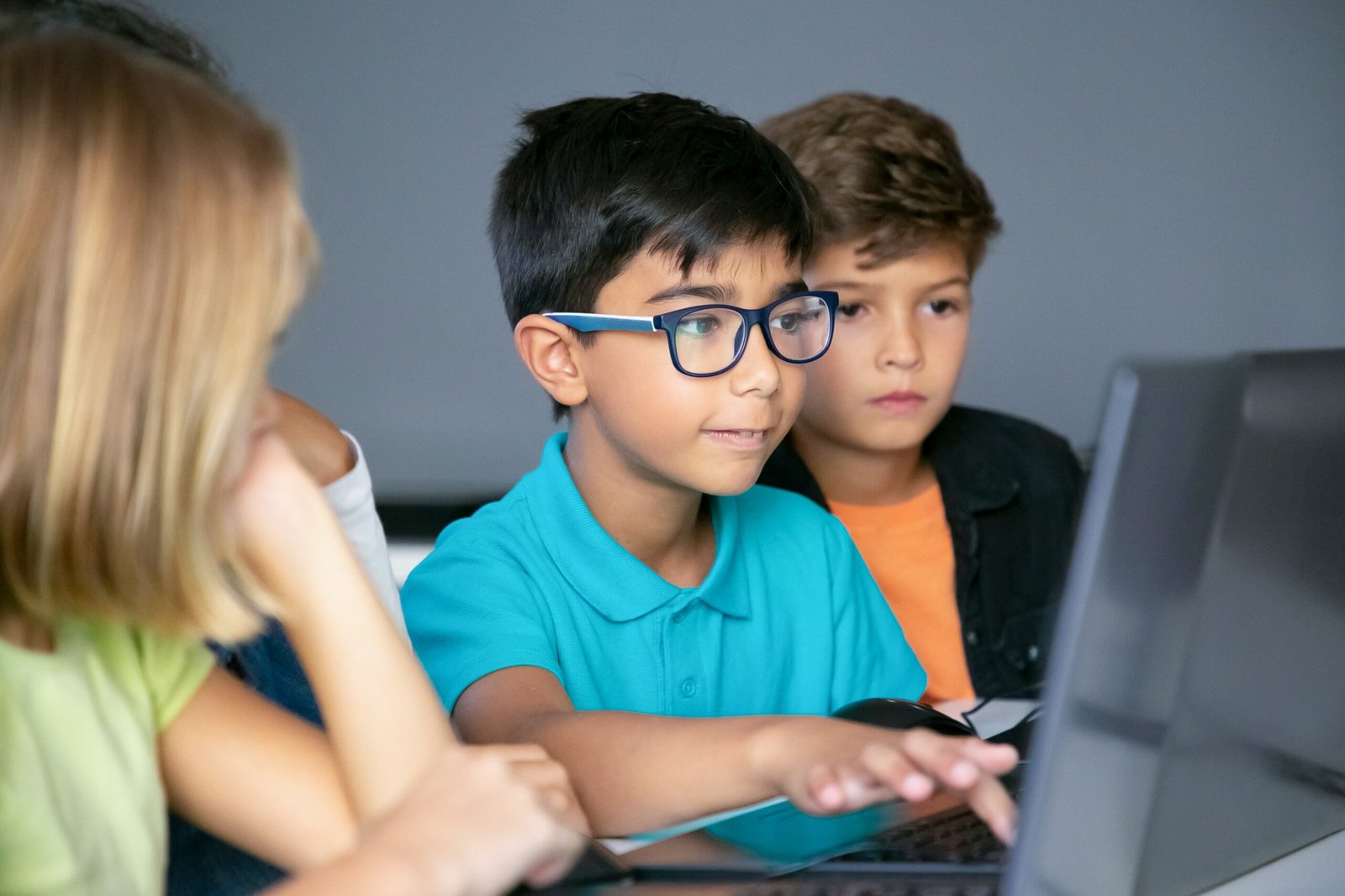 asian boy typing laptop keyboard classmates sitting table watching him doing task together min scaled